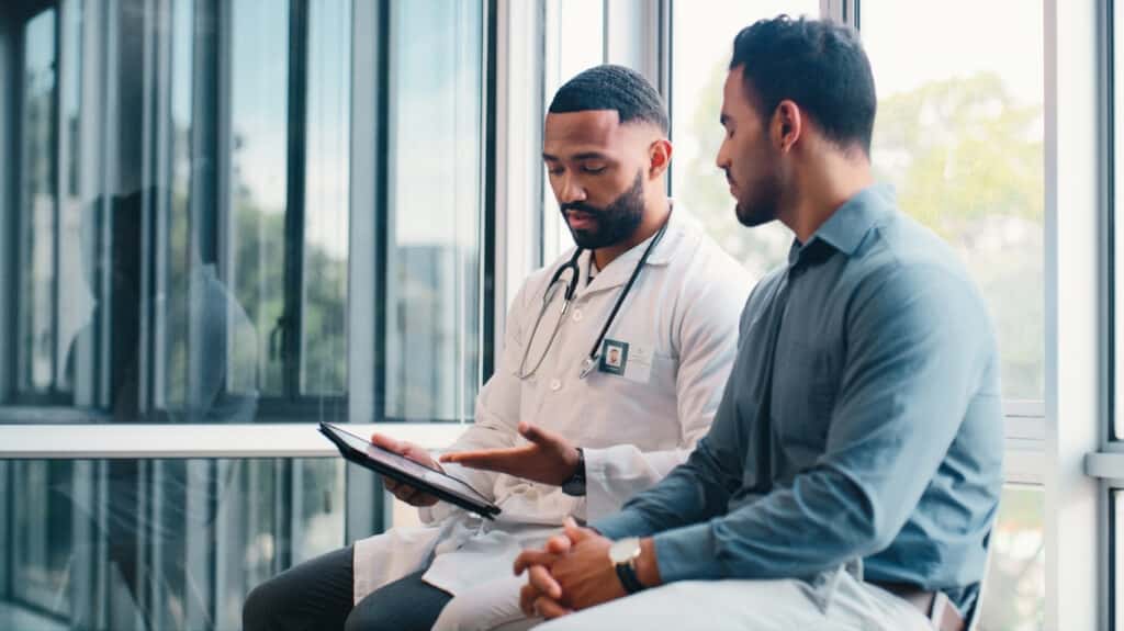 doctor reviewing medical information on a tablet with a male patient