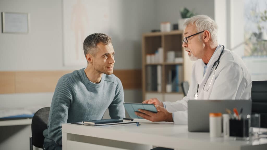 doctor reviewing medical results on a tablet with a middle-aged male patient